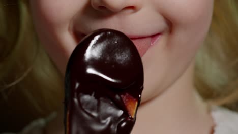 Playful-teen-child-kid-girl-eating,-licking-melted-chocolate-sweet-candy-syrup-from-wooden-spoon
