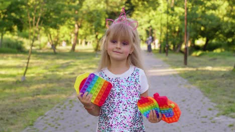 Child-girl-kid-holding-many-colorful-squishy-silicone-bubbles-sensory-toy,-kid-playing-pop-it-game
