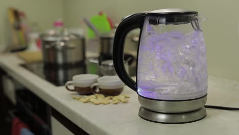 Tea-kettle-with-boiling-water.-Tea-bags-and-sugar-on-the-background
