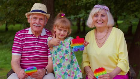 Lächelnde-ältere-Großmutter,-Großvater-Und-Enkelin-Spielen-Ein-Anti-Stress-Spielzeug-Zum-Quetschen
