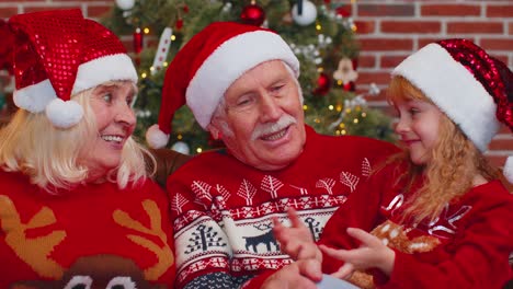 Glückliche-ältere-Großeltern-Mit-Enkelin-Genießen-Angenehme-Gespräche-Im-Weihnachtsheimzimmer