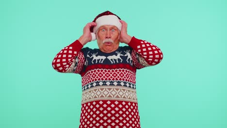 Grandfather-in-New-Year-deer-sweater-raising-hands-in-surprise-shocked-by-sudden-victory-wow-emotion