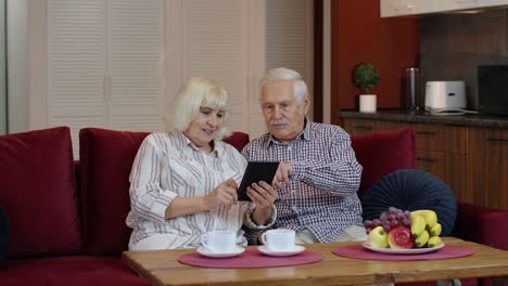 Älteres,-Altes-Großelternpaar,-Das-Zu-Hause-Mit-Einem-Digitalen-Tablet-Computer-Spricht-Und-Online-Einkauft
