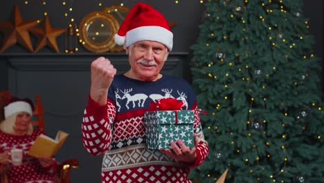 Senior-Großvater-Im-Weihnachtspullover-Feiert-Erfolg-Sieg-Schrei-Macht-Gewinner-Hände-Geste