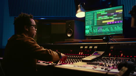 African-american-producer-working-at-mixing-panel-in-recording-studio