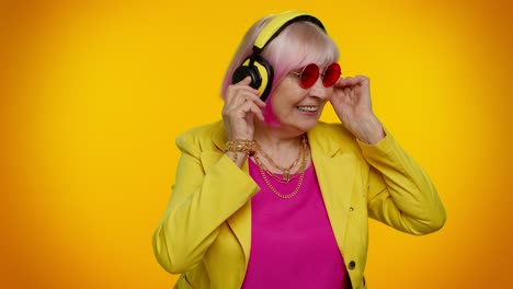 Senior-woman-listening-music-on-headphones-dancing-disco-fooling,-having-fun,-gesticulating-hands