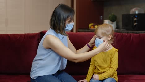 Mother-puts-on-little-sick-daughter-protective-medical-mask-at-home.-Coronavirus-quarantine-lockdown