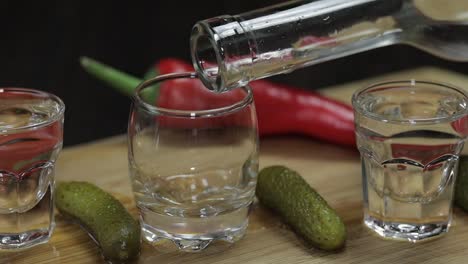 Pour-vodka-into-shot-glasses-placed-on-a-wooden-board