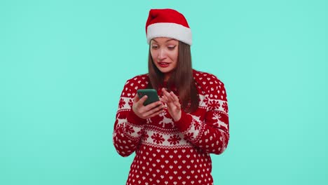 Erwachsenes-Mädchen-Im-Roten-Weihnachtspullover-Schaut-Auf-Smartphone-Display-Und-Freut-Sich-Aufrichtig-über-Erfolg-Und-Glück
