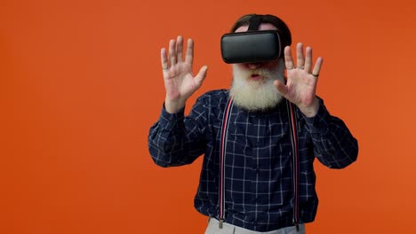 Elderly-stylish-gray-haired-man-using-headset-helmet-app-to-play-simulation-virtual-reality-VR-game