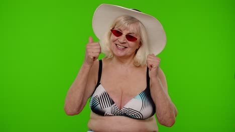 Senior-pensioner-woman-tourist-in-swimsuit-bra,-red-sunglasses-and-hat-dancing-celebrating,-smiling