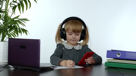 Teen-school-girl-wearing-wireless-headphones-calling-teacher-on-mobile-phone.-Distance-education