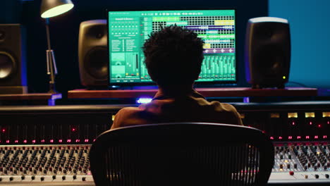 African-american-sound-producer-editing-tracks-on-audio-software-and-console