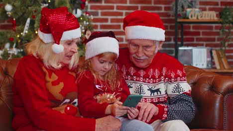 Senior-family-grandparents,-granddaughter-purchase-online-Christmas-gifts-on-mobile-phone,-shopping