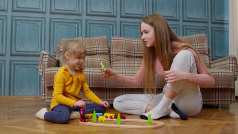 Mother-playing-with-child-kid-daughter-riding-toy-train-on-wooden-railroad-blocks-board-game-at-home