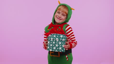 Cheerful-girl-in-Santa-sweater-presenting-one-Christmas-gift-box,-stretches-out-her-hands-to-camera