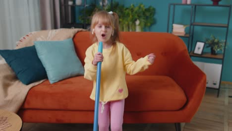 Funny-toddler-girl-kid-cleaning-washes-floors-with-a-mop-at-home-dancing,-singing-in-positive-mood