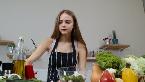 Chica-Vegana-Cocinando-Ensalada-Con-Verduras-Crudas-Mientras-Busca-En-El-Teléfono-Móvil-Una-Receta-En-Línea