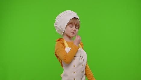 Child-girl-kid-dressed-as-cook-chef-raising-hands,-showing-tasty-gesture,-smiling,-looking-at-camera