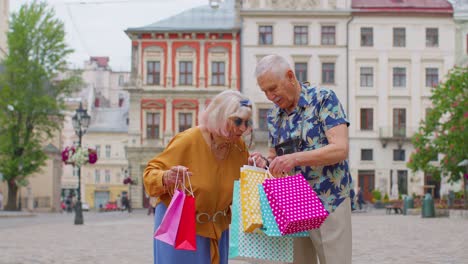 Älteres,-Stilvolles-Touristenpaar,-Mann-Und-Frau,-Die-Nach-Dem-Einkaufen-Im-Einkaufszentrum-Mit-Bunten-Taschen-Spazieren-Gehen