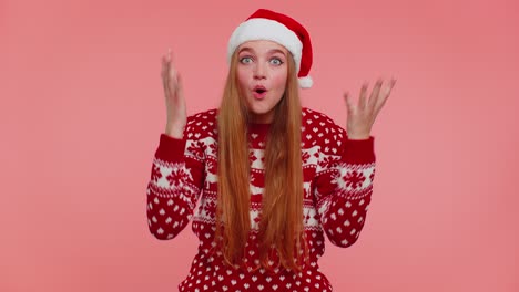 Teen-adult-girl-in-Christmas-hat-raising-hands-in-surprise-shocked-by-sudden-victory,-wow-emotion
