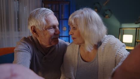POV-of-cheerful-happy-Caucasian-senior-married-family-couple-talking-on-video-call-at-evening-home