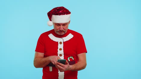 Man-in-fashionable-Christmas-t-shirt-looking-smartphone-display-sincerely-rejoicing-win-success-luck