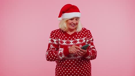 Ältere-Großmutter-Tippt-Mit-Dem-Mobiltelefon-Neue-Beiträge-Im-Internet,-Weihnachtseinkäufe-Online,-Surfen