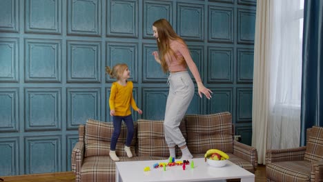 Happy-funny-family-mother-and-child-kid-daughter-dancing,-jumping-on-sofa,-listening-music-at-home