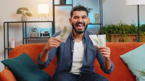 Excited-happy-Indian-man-showing-money-dollar-cash-bills-satisfied-of-income-saves-salary-earnings