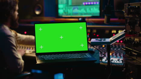 Sound-designer-uses-audio-mixer-and-greenscreen-layout-in-professional-studio