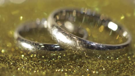 Wedding-silver-rings-lying-on-shiny-glossy-surface.-Shining-with-light.-Close-up