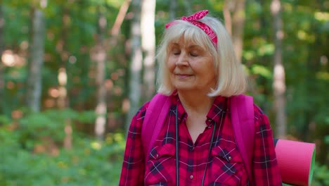 Senior-grandmother-tourist-engaged-in-Nordic-walking-sport-hiking-with-backpacks,-trekking-poles