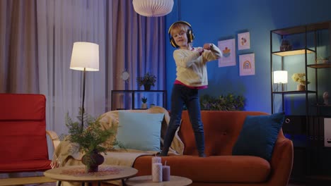 Happy-child-girl-kid-in-headphones-dancing-moving-to-rythm-while-listening-to-music-at-home-alone