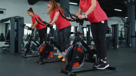 Sportliche-Frauengruppe,-Die-Auf-Einem-Stationären-Spinning-Fahrrad-Trainiert,-Im-Fitnessstudio,-Gewichtsverlust-Im-Innenbereich