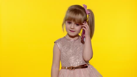 Young-modern-child-girl-in-dress-communicates-on-mobile-phone,-smiles-and-talks.-Yellow-background