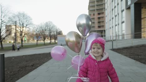 Glückliches-Kind-Läuft-Mit-Heliumballons-Die-Straße-Entlang