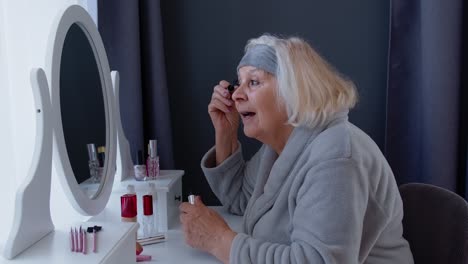 Old-senior-woman-grandmother-applying-eyelash-mascara,-putting-makeup-on,-taking-care-of-skin