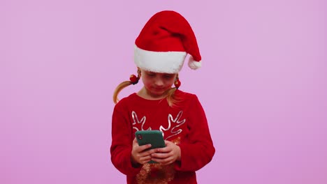 Glückliches-Mädchen-Im-Weihnachtspullover-Mit-Hirschen-Auf-Dem-Smartphone-Display,-Das-Aufrichtig-über-Erfolg-Und-Glück-Lacht