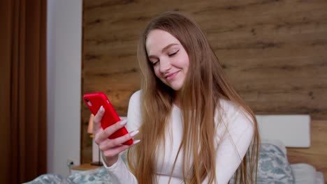 Girl-looks-at-screen-of-mobile-smartphone-makes-successful-online-order,-smiles-and-looks-at-camera