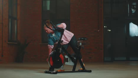 Sportliches-Mädchen,-Das-Aerobes-Stretchingtraining-Auf-Dem-Fahrrad-Heimtrainer-Durchführt