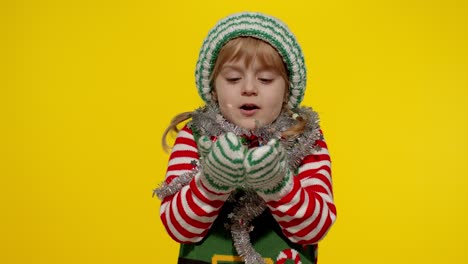 Kid-child-teenager-girl-in-Christmas-elf-Santa-helper-costume-having-fun-blowing-confetti-to-camera