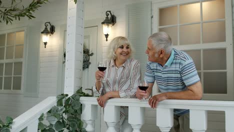 Älteres,-Kaukasisches-Paar-Trinkt-Wein-Auf-Der-Veranda-Zu-Hause.-Glückliche,-Reife-Rentnerfamilie-Ruht-Sich-Aus
