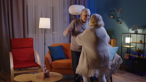 Happy-senior-people-couple-dancing-at-home-relaxing-having-fun-with-modern-music-smiling-at-home