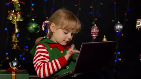 Kleines-Mädchen-Im-Weihnachtselfenkostüm,-Das-Mit-Dem-Laptop-Online-Einkauft-Und-In-Sozialen-Medien-Surft