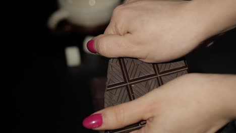Woman-breaks-black-chocolate-bar.-Close-up.-Slow-motion