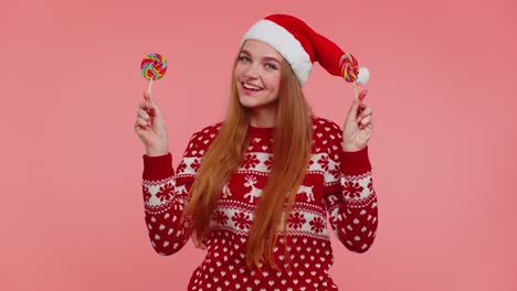 Funny-girl-in-New-Year-sweater-holding-candy-striped-lollipops-hiding-behind-them,-fooling-around