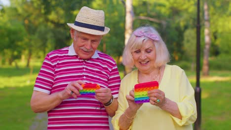 Lächelnde-ältere-Alte-Großmutter-Großvater-Spielt-Anti-Stress-Touchscreen-Push-Pop-Es-Beliebtes-Spielzeug