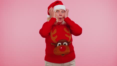 Grandmother-in-New-Year-deer-sweater-raising-hands-in-surprise-shocked-by-sudden-victory-wow-emotion