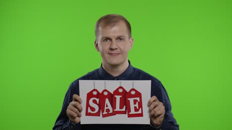 Cheerful-blonde-guy-showing-Sale-word-advertisement.-Online-shopping-with-low-prices-on-Black-Friday